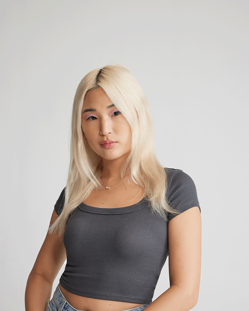A woman with blonde hair extensions wearing a light black top.