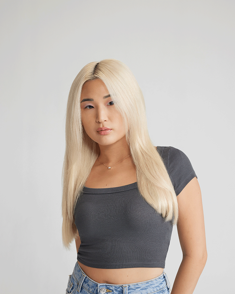 A woman with long blonde hair, enhanced by extensions, wearing stylish jeans.