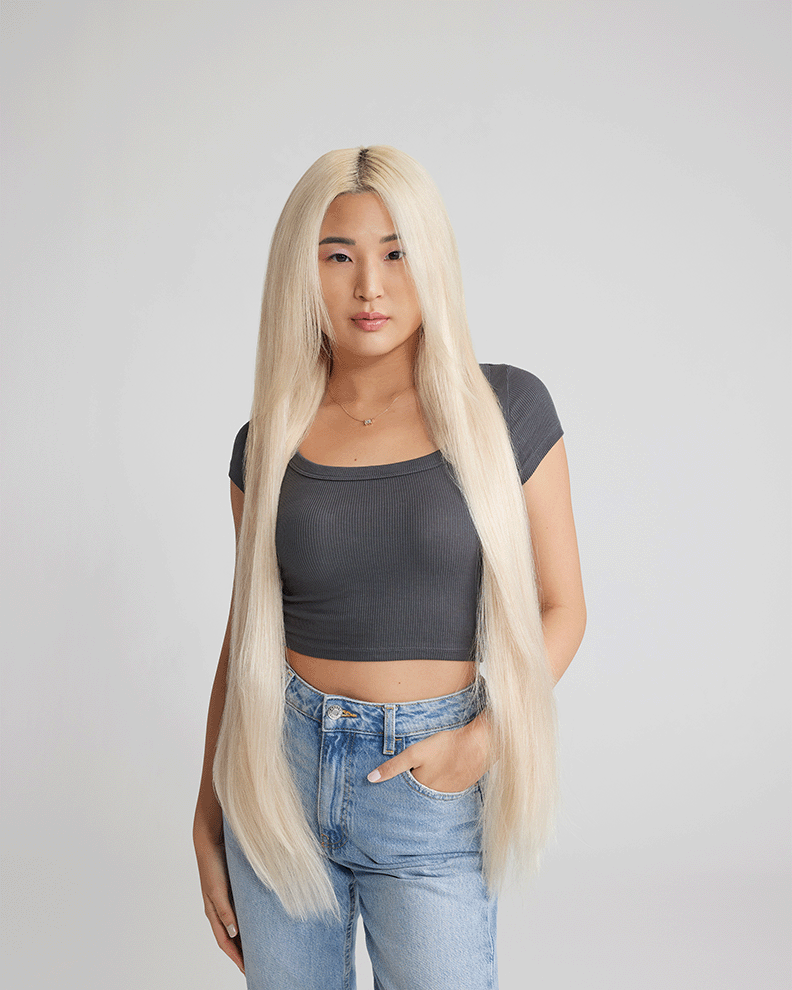 A woman with long, straight blonde hair enhanced by extensions, elegantly dressed, showcasing her stylish look.