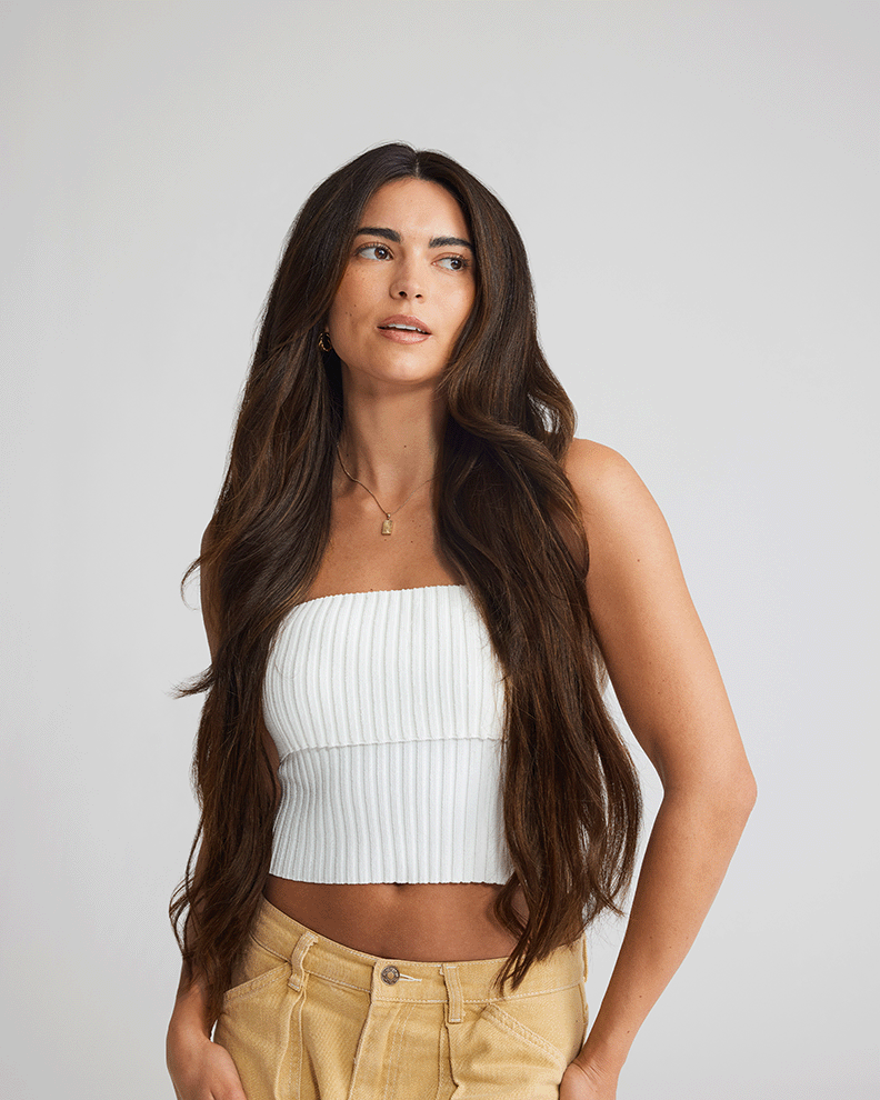 A woman in a crop top and khaki pants, showcasing her hair extensions and stylish outfit.