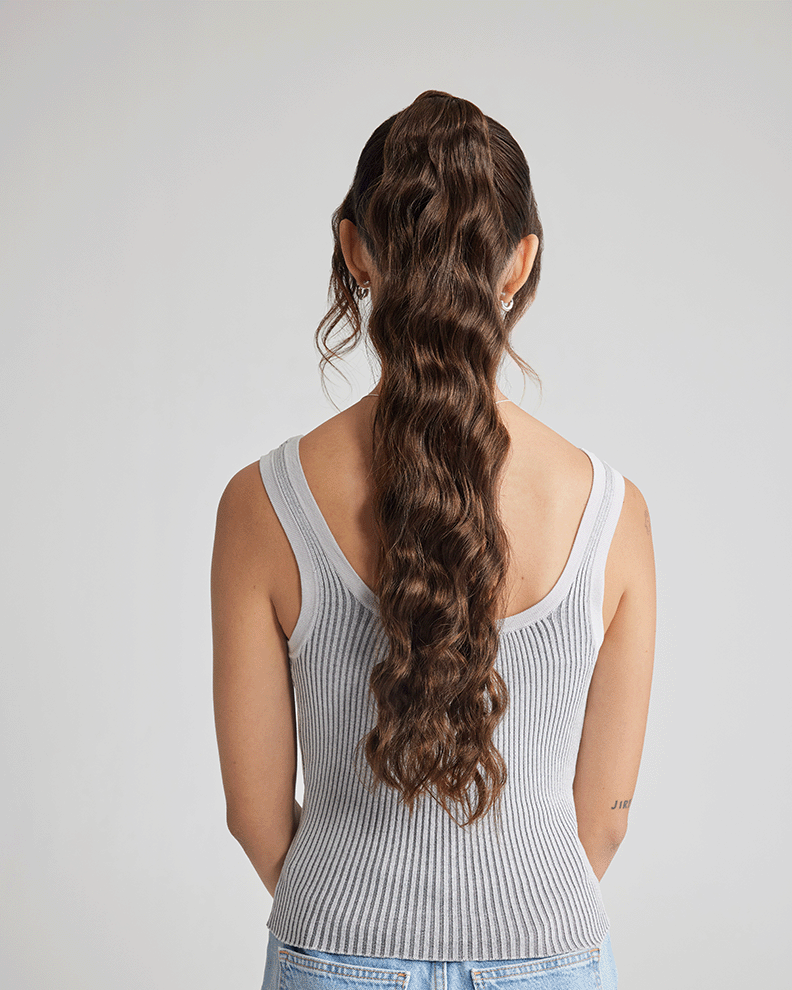 A back view of a woman displaying her long, wavy hair after the application of hair extensions.