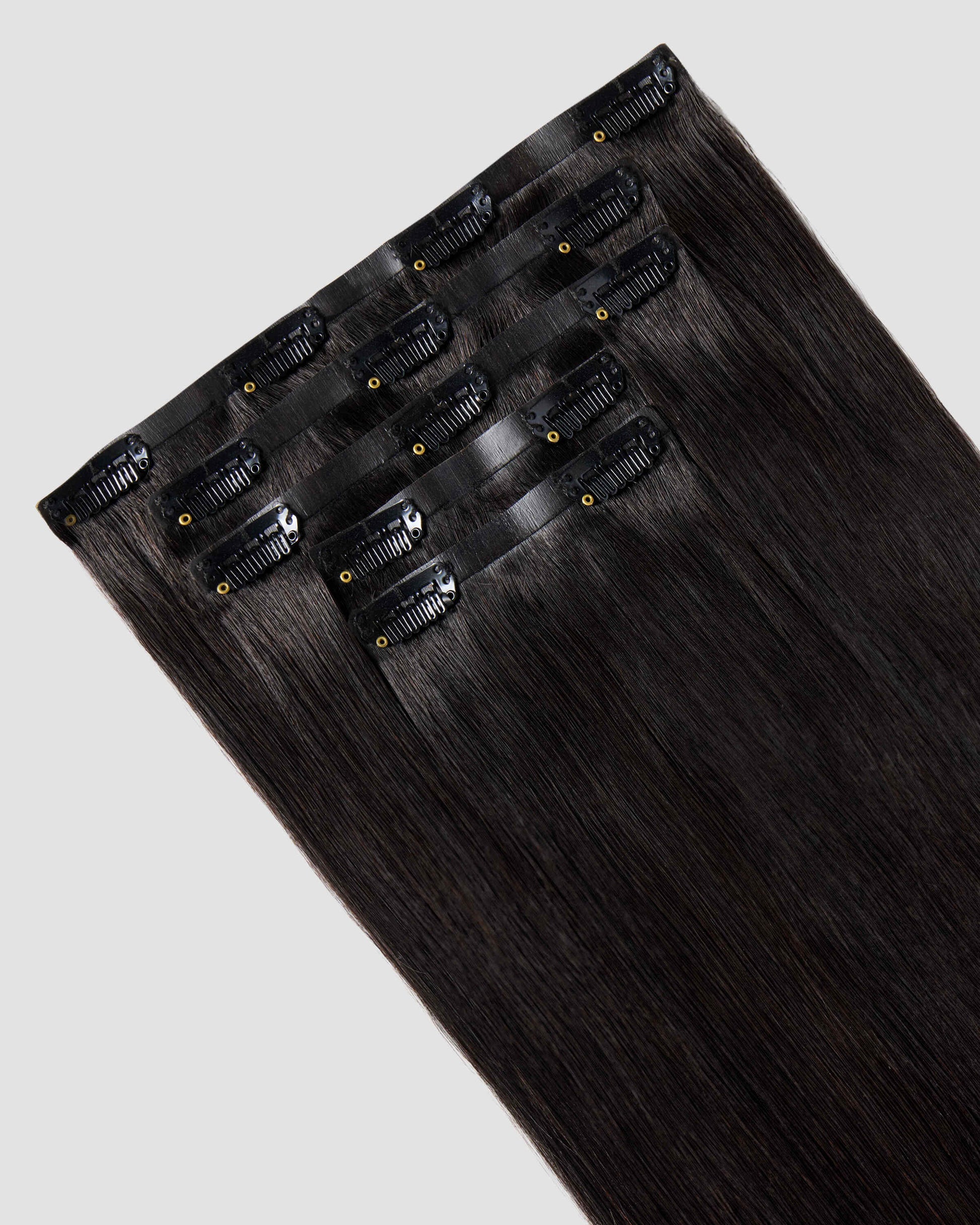 A set of clip-in hair extensions in natural black, highlighting their seamless design and rich, vibrant color.
