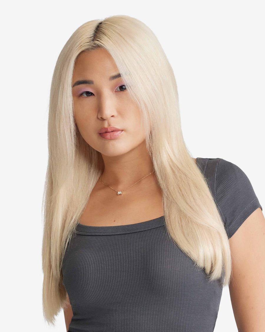 A blonde woman with long Zala hair extensions is dressed in a grey top.
