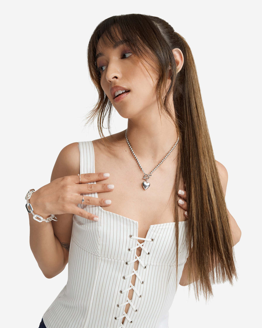 A woman with long brown Zala hair extensions in a ponytail, wearing a white top.