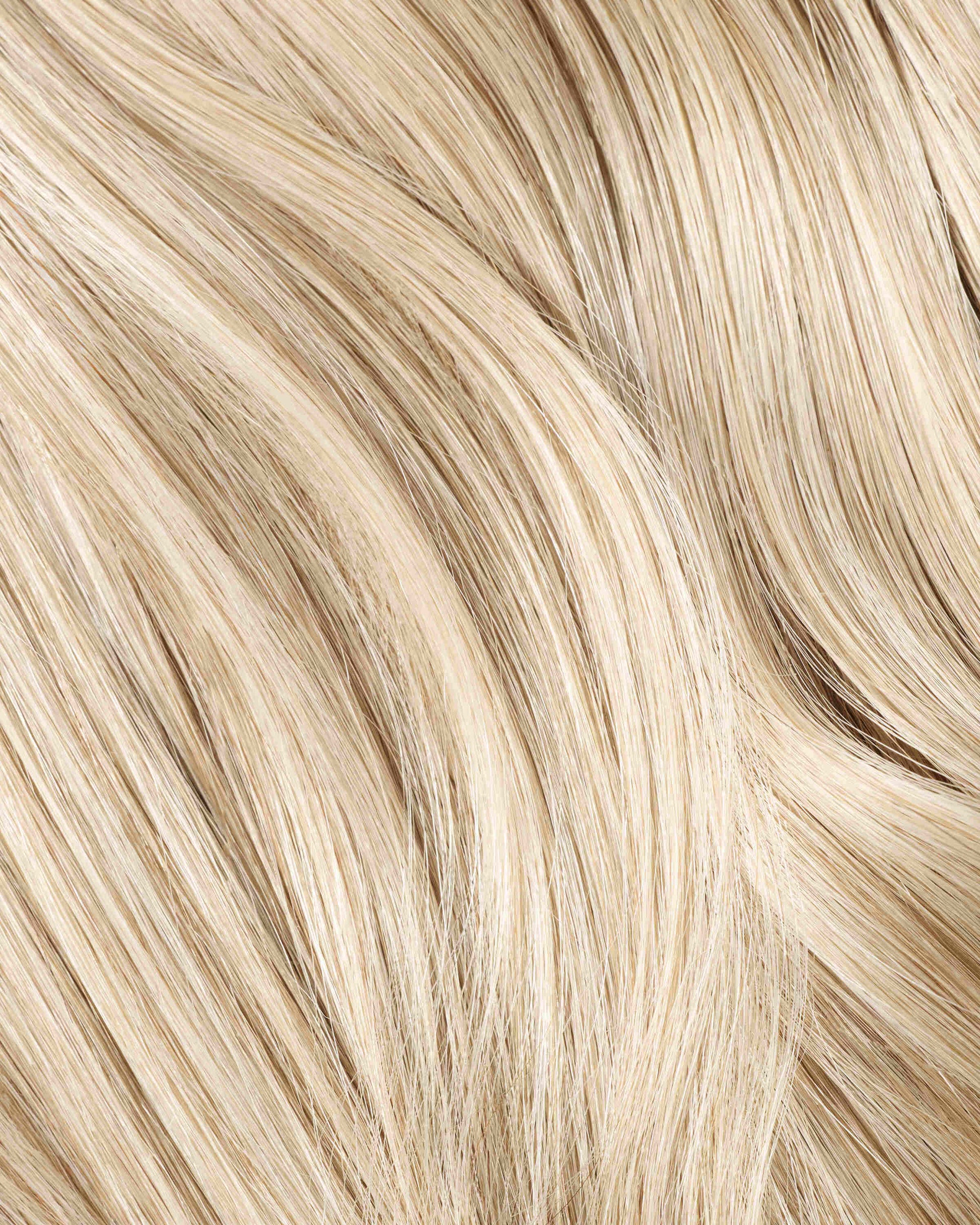 A close-up of a champagne blonde hair extension featuring wavy hair, showcasing its rich texture and vibrant color.