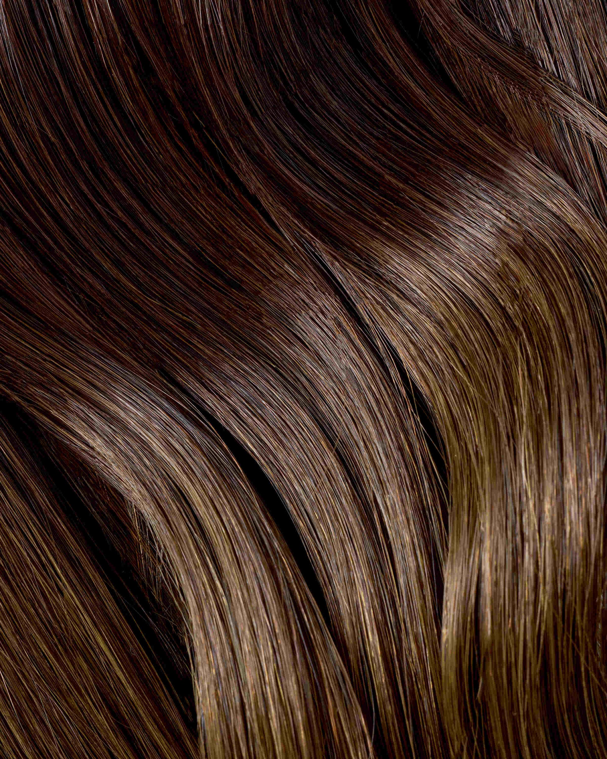 A close-up of chocolate swirl extensions with rich brown and blonde highlights.