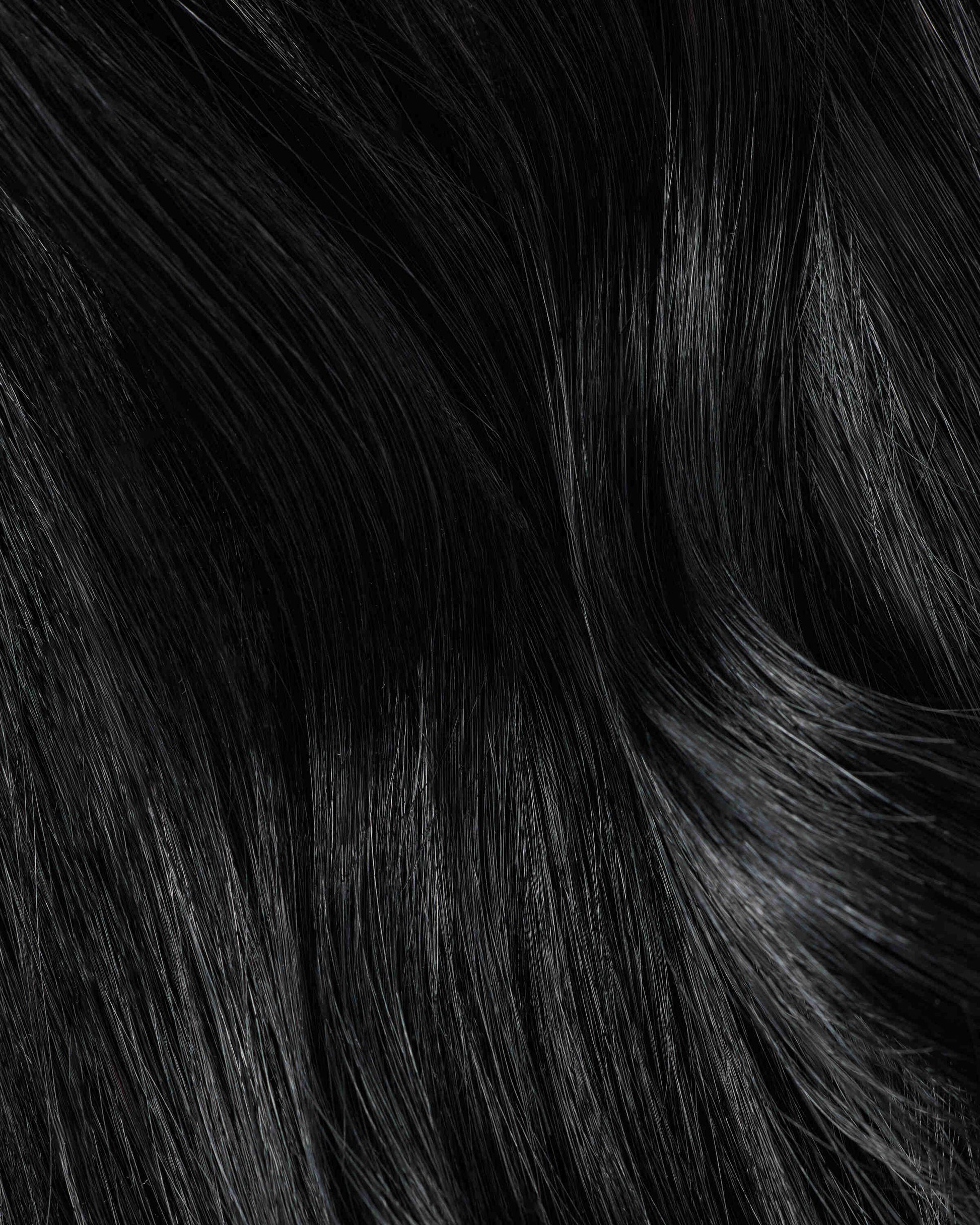 A close-up of jet black hair extensions showcasing a rich, textured black hair extension.