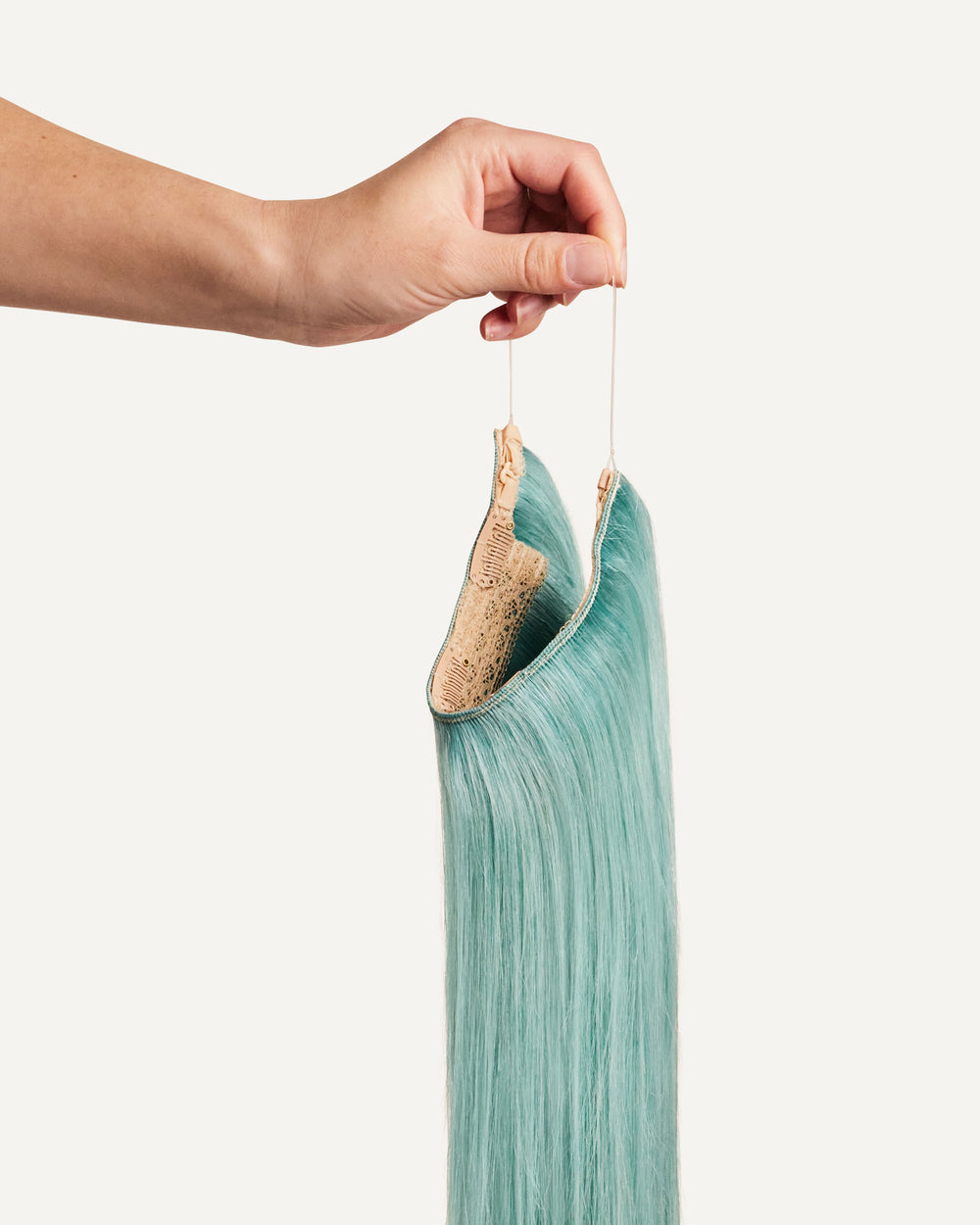 A close-up of a Zala Halo Hair Extension in a vibrant aquamarine shade.