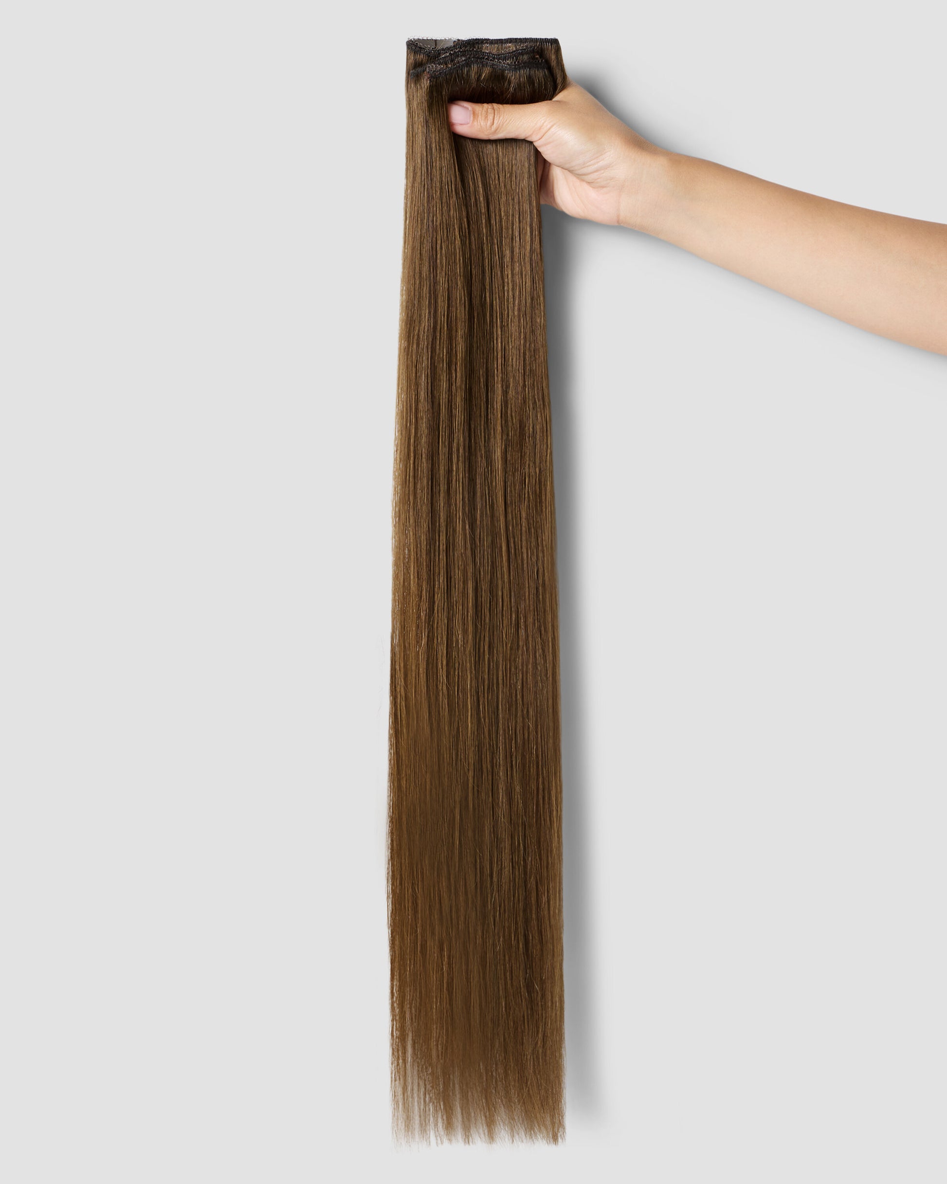 A detailed view of a brown hair extension, highlighting the chestnut hue and weave-in design for a natural look.