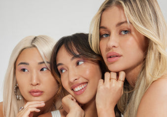 A joyful photo of three women with hair extensions, standing together and smiling, highlighting their fashionable hairstyles.