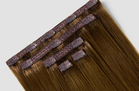 Brown clip-in hair extensions are displayed on a white background.