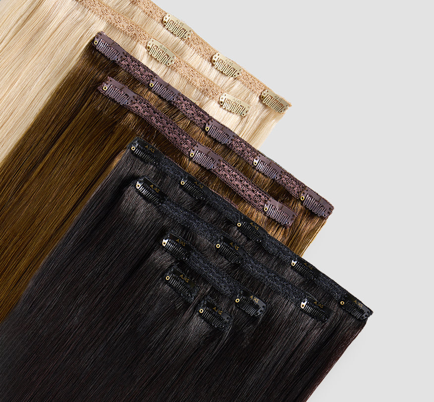 A variety of clip-in hair extensions are displayed in multiple colors.