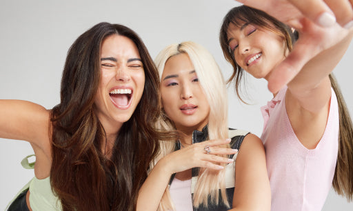 Three women with hair extensions smiling, having fun, and posing together for a selfie, capturing a joyful moment.