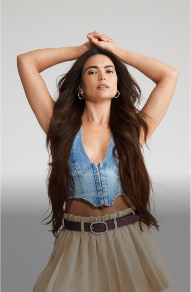 A woman with long hair extensions wearing a blue top placed her hands on her head.