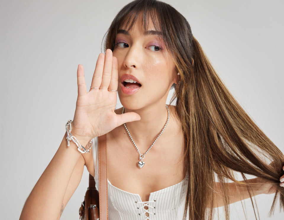 A woman with long Zala hair extensions, wearing a dress and silver jewelry, including a necklace.