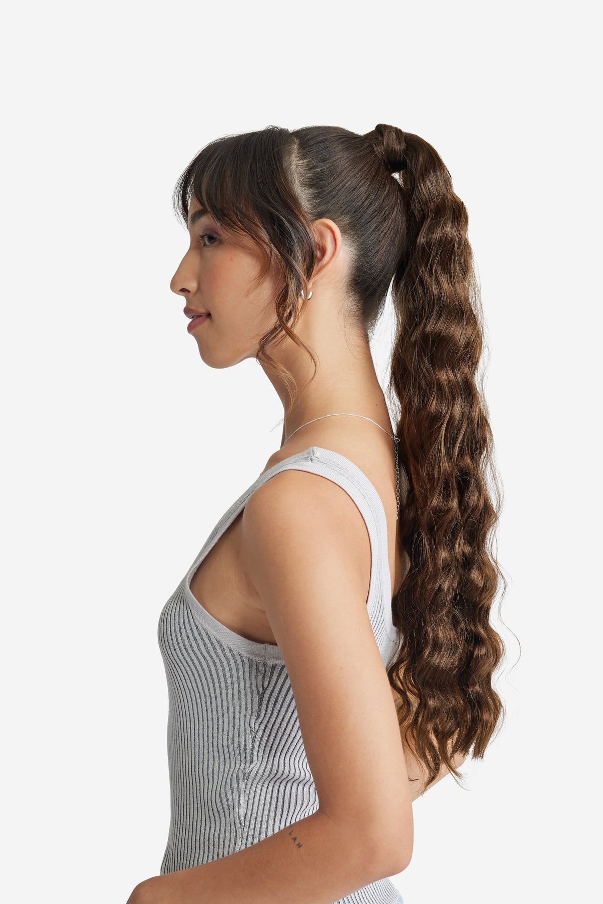 A sideview of a woman with a ponytail, showcasing applied hair extension for added length and volume.