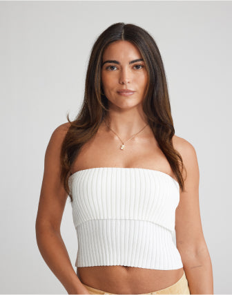 A women wearing a white ribbed crop top made of soft, stretchy knit, and brown hair extensions for a stylish look.