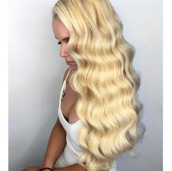 Side profile of a woman with long, voluminous, platinum blonde hair styled in soft waves with the cosmo wand.