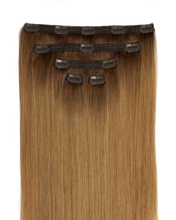 A clip-in hair extension is displayed in long, straight blonde hair, enhancing volume and length for a stylish look.