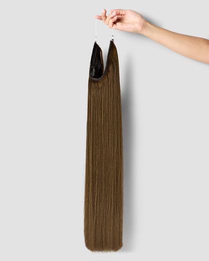 A hand gently holds long chestnut brown hair extensions, showcasing their rich color and texture. 