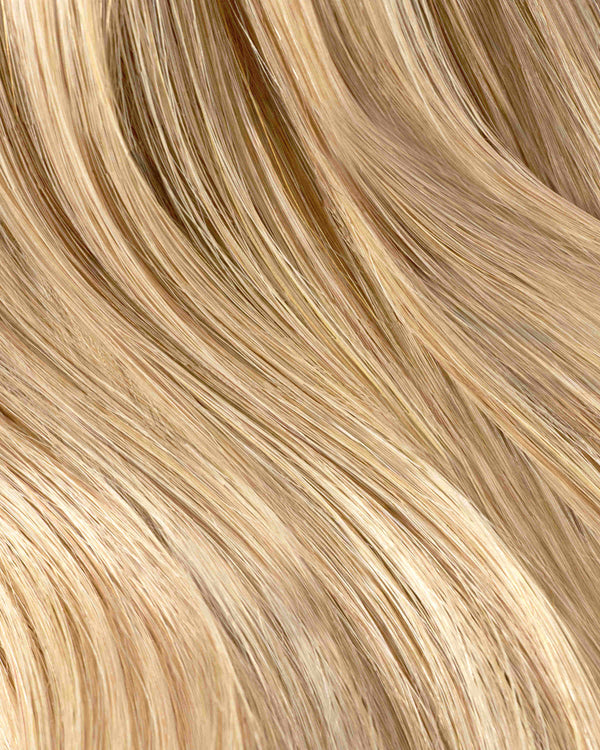 A close-up of wavy honey blonde hair extensions, showcasing soft, light blonde strands with a natural shine.