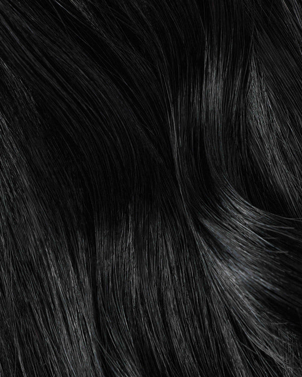 A close-up of jet black hair extensions showcasing a rich, textured black hair surface.