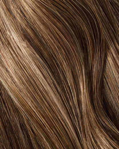 A swatch of hair with brown and blonde highlights, emphasizing the beauty of hair extensions.