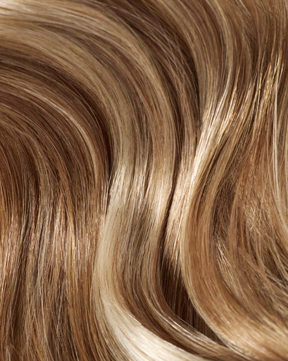 A close-up of hair with sun-kissed blonde and brown highlights, showcasing vibrant hair extensions.