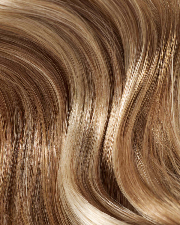 A close-up hair swatch of sun-kissed blonde and brown colored hair extensions.