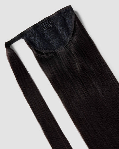 A sleek black hair clip holding long, straight natural black ponytail hair extensions elegantly styled.