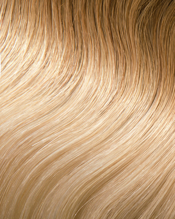 A close-up of blonde hair extensions featuring wavy textures with light and dark tones for a dynamic look.