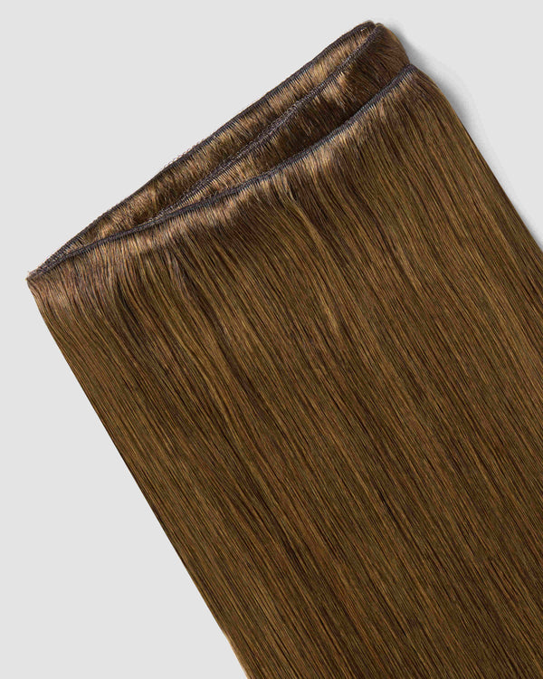 A detailed view of a brown hair extension, highlighting the chestnut hue and weave-in design for a natural look.