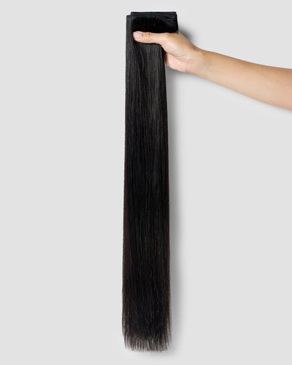 A hand gently holding a long strand of natural black hair, showcasing a hair extension's seamless blend and elegance.