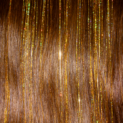 A swatch of hair with gold glitter and tinsel yellow hair extensions, creating a shimmering effect.